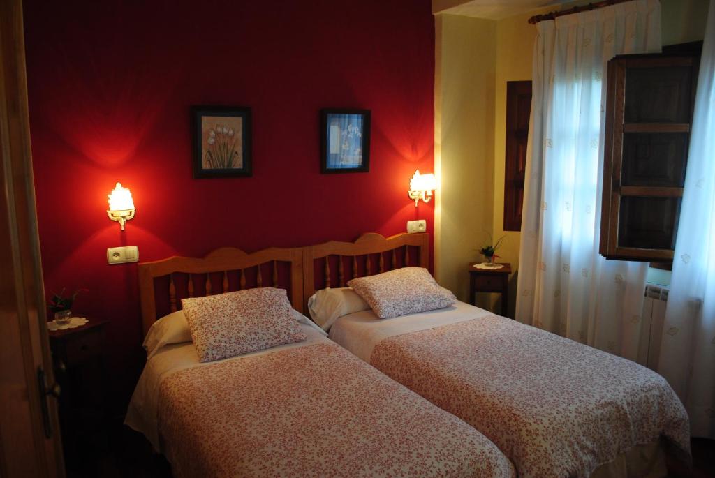 2 camas en una habitación con paredes rojas en Astur Regal, en Cadavedo