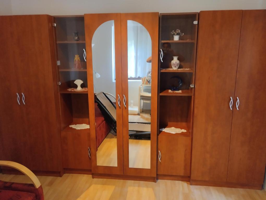 a wooden cabinet with a mirror in a room at Aliz és Martin vendégház in Balatonmáriafürdő