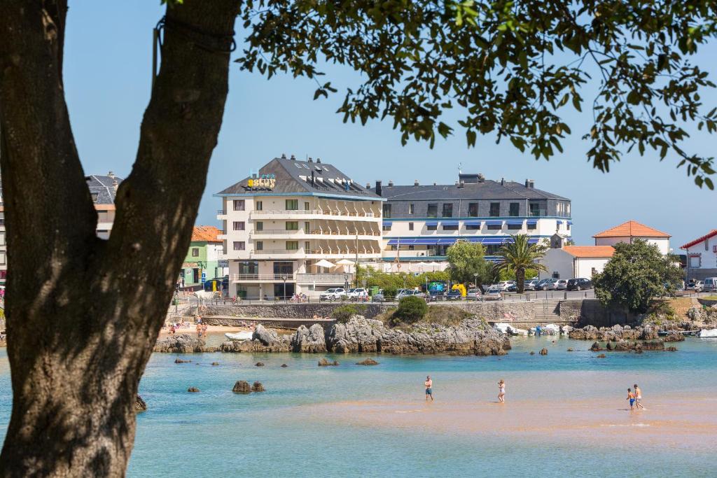 people on a beach with buildings in the water at Apartamentos Astuy in Isla