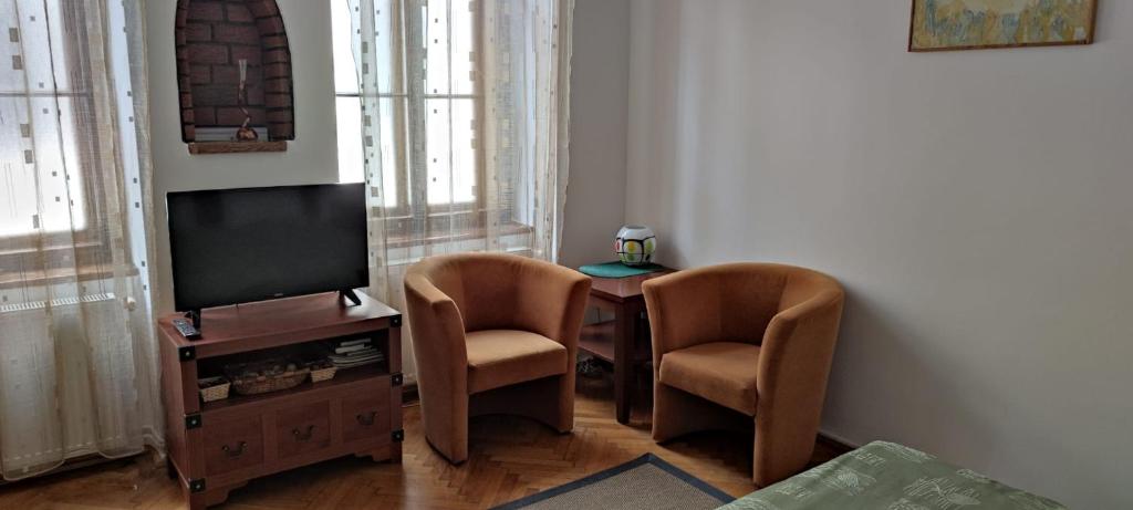 sala de estar con mesa, 2 sillas y TV en Garsoniera Central Sibiu, en Sibiu