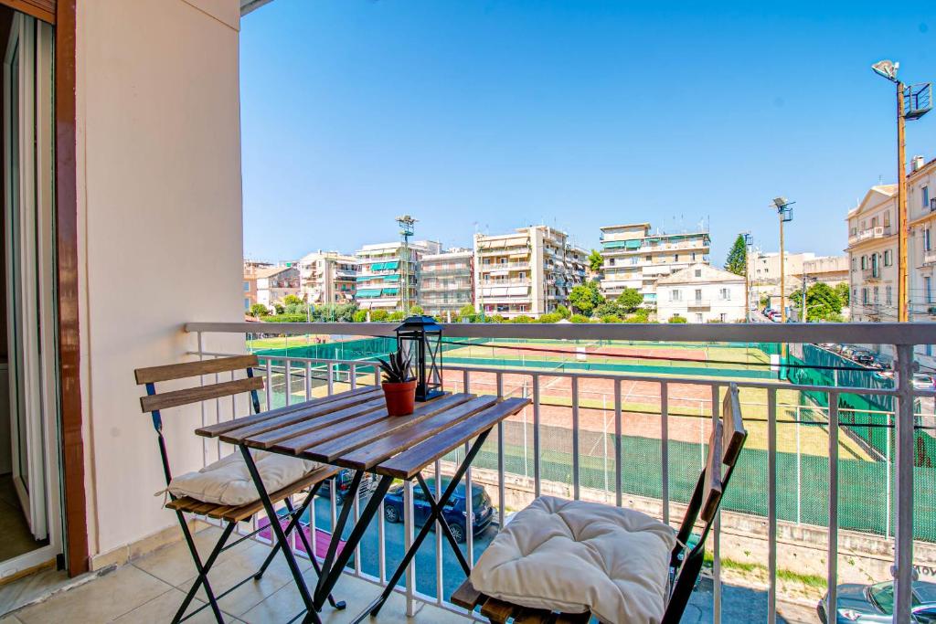 a table and chairs on a balcony with a tennis court at Match Point Apartment, Corfu Town in Ágios Rókkos