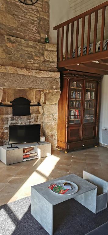uma sala de estar com uma mesa e uma parede de pedra em Cottage LE NID em Perriers-en-Beauficel