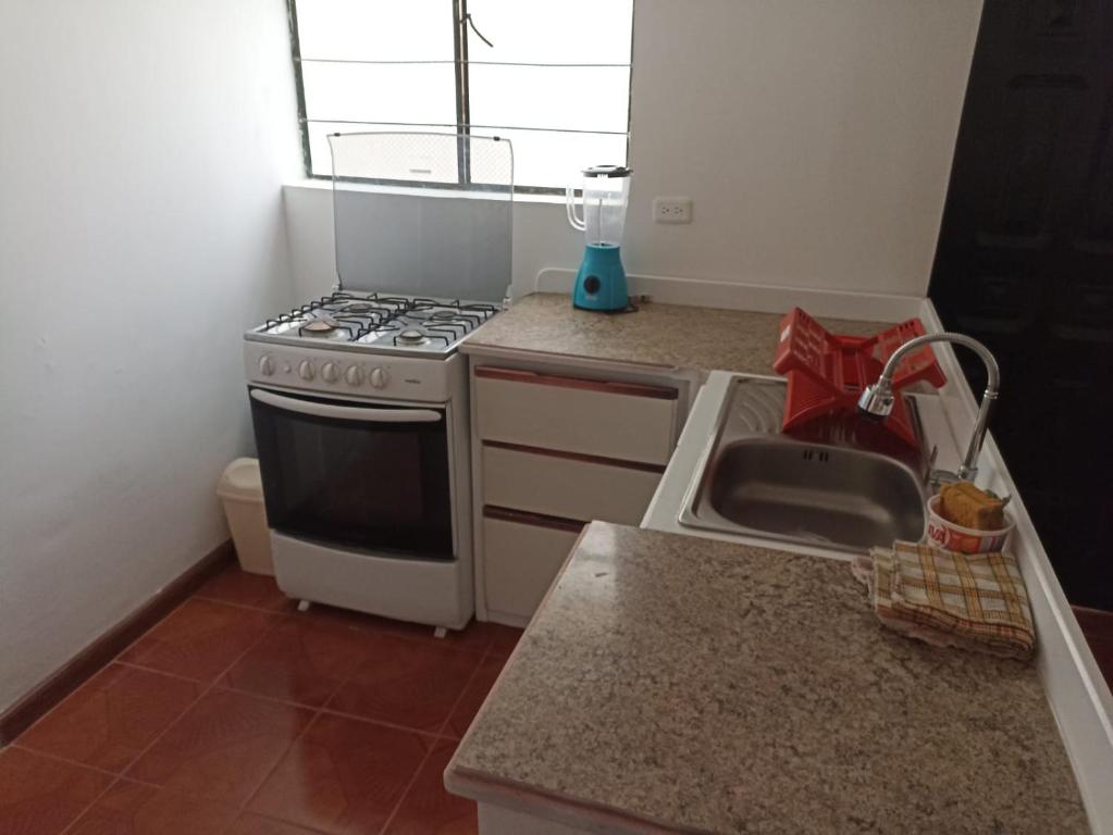uma cozinha com um fogão e um lavatório em GARDENIAS SUITS em Ibarra