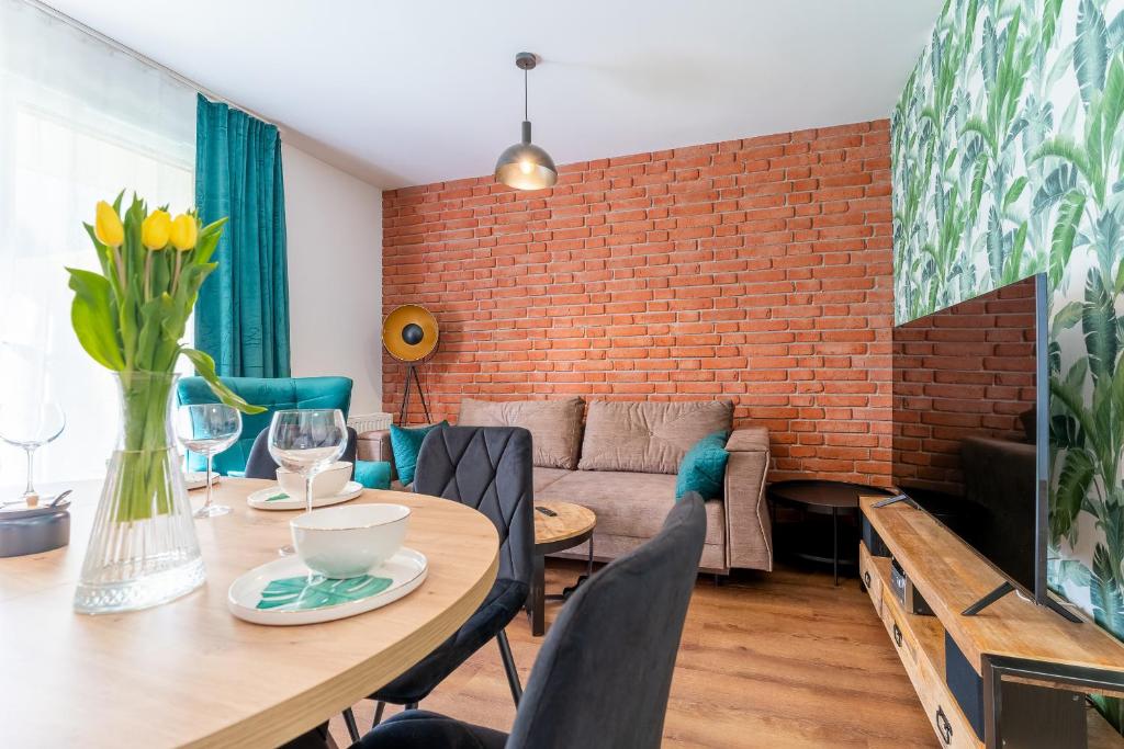 a living room with a table and a brick wall at Apartamenty w Karkonoszach- Apartament Lucky 7 z widokiem na Śnieżkę i ogródkiem in Karpacz