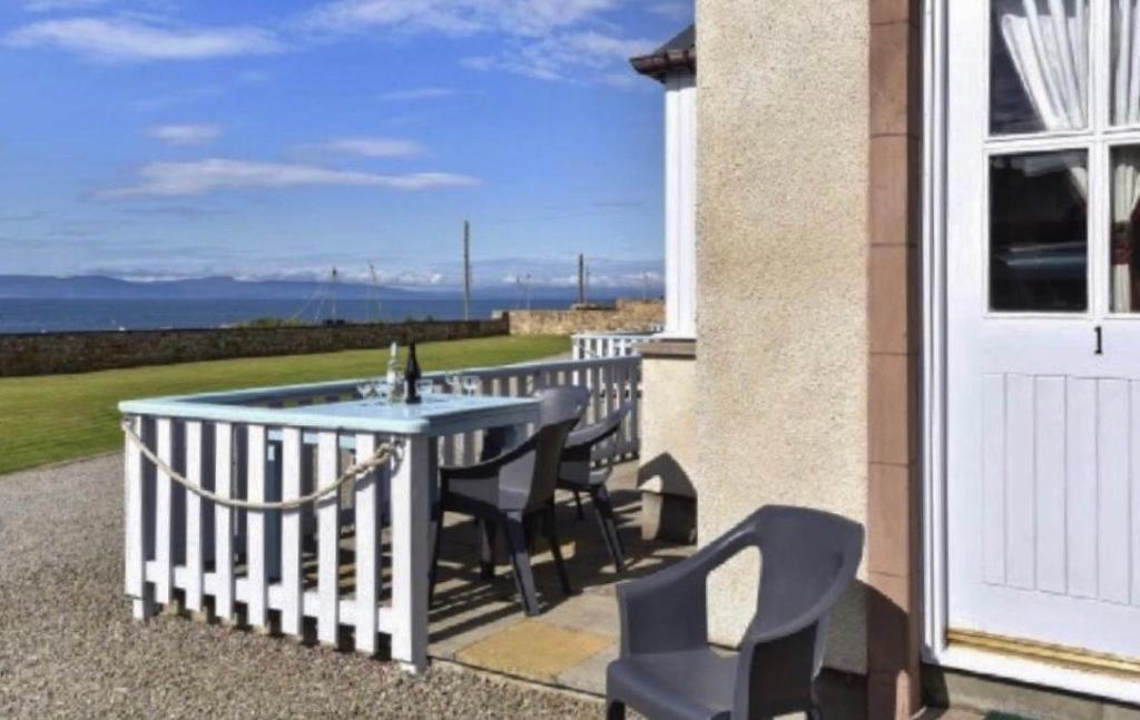 a patio with a table and chairs on a balcony at Dolphin View Cottages 2 in Portmahomack