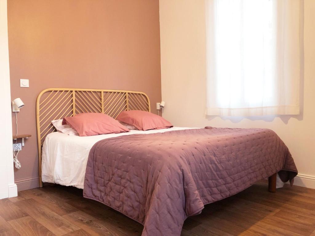 Un dormitorio con una cama con almohadas rosas y una ventana en Le songe d'Etigny, en Luchon