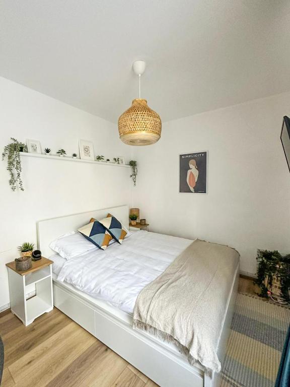 a bedroom with a white bed and a chandelier at Zen Studio - Edge of Old Town with Free Private Parking in Braşov