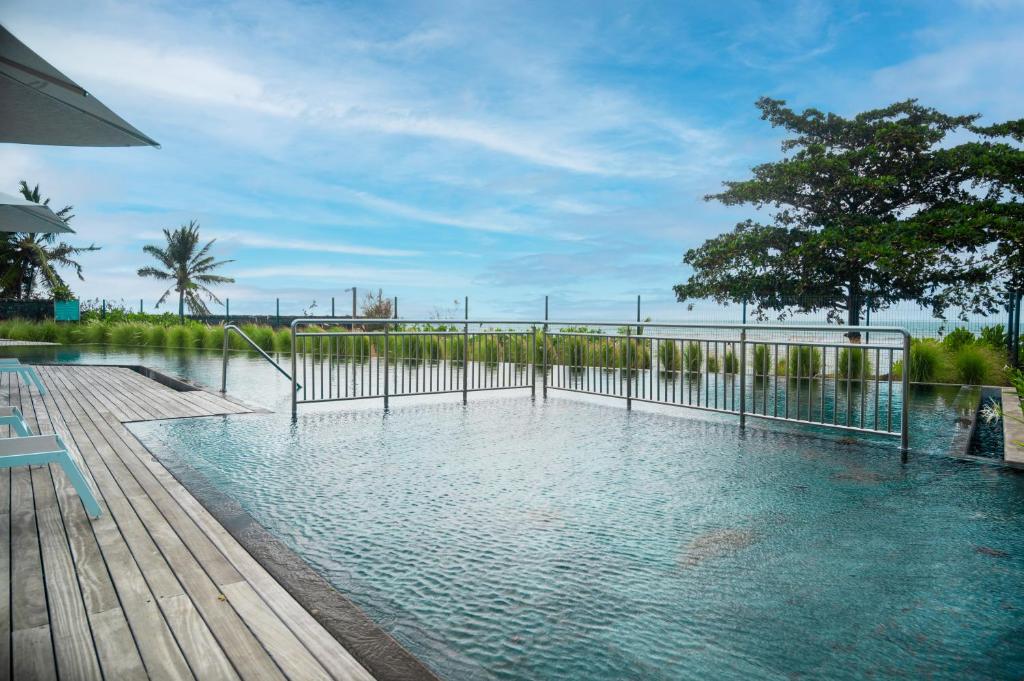 a swimming pool with a fence and trees and water at Ocean Point Beachfront Residences - Apartment A1 in Pointe aux Piments