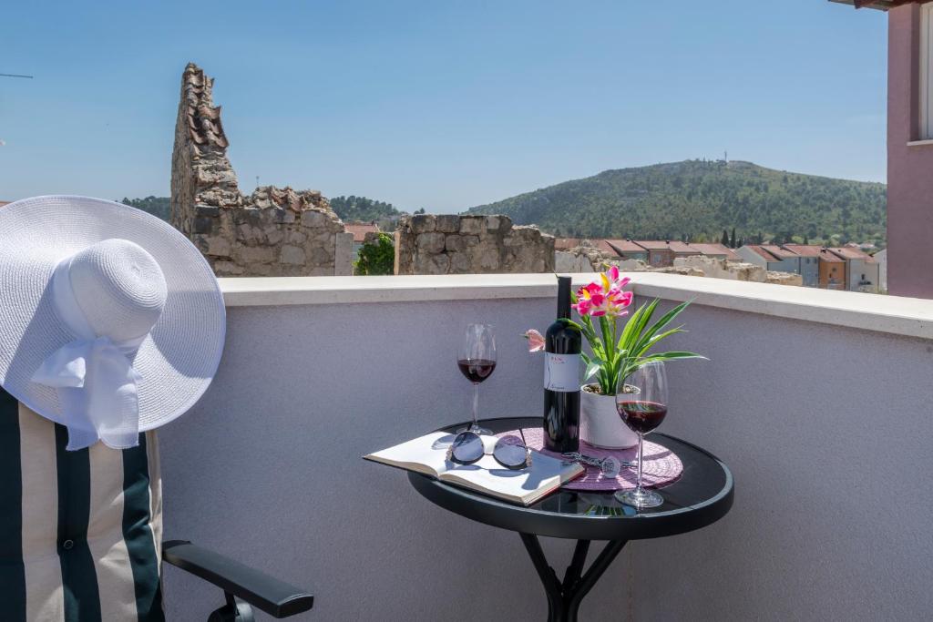 un tavolino con bicchieri da vino e fiori sul balcone di Apartments Lana a Mlini