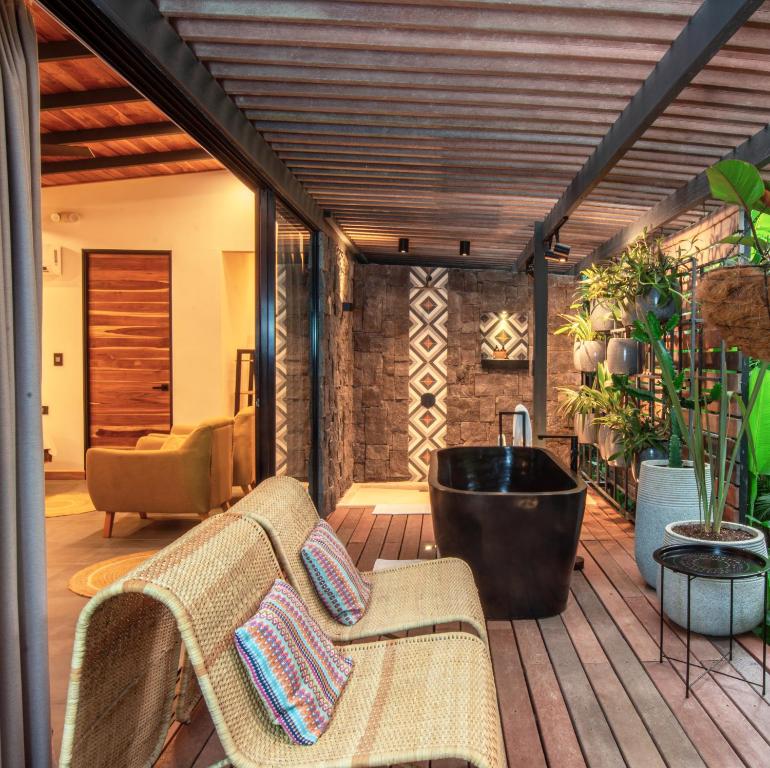 a deck with a bath tub and a chair at Exôtico Beach & Rooms in Puerto Viejo
