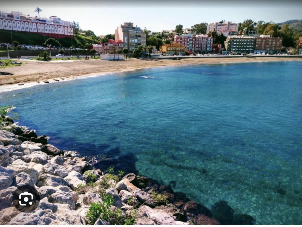 una playa con agua azul y edificios de fondo en Apartamentos Murallas Merinies, en Ceuta