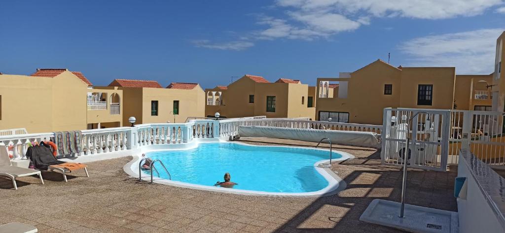 a swimming pool with a person sitting in a chair next to a building at PARAISO DE LUX in Costa de Antigua
