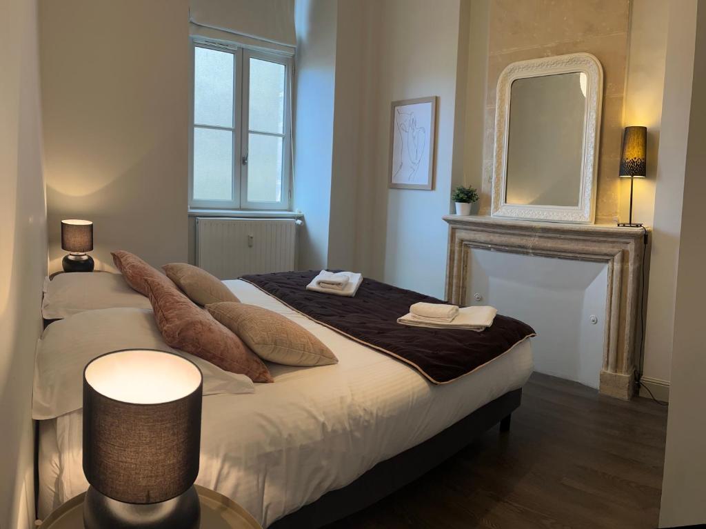 a bedroom with a bed with a mirror and a fireplace at Appartement de charme in Bayeux