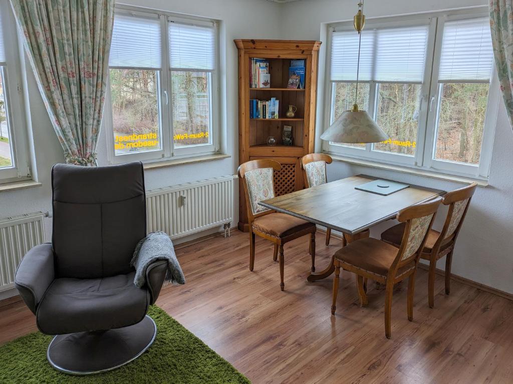 uma sala de jantar com mesa, cadeiras e janelas em Strandnest em Ostseebad Karlshagen