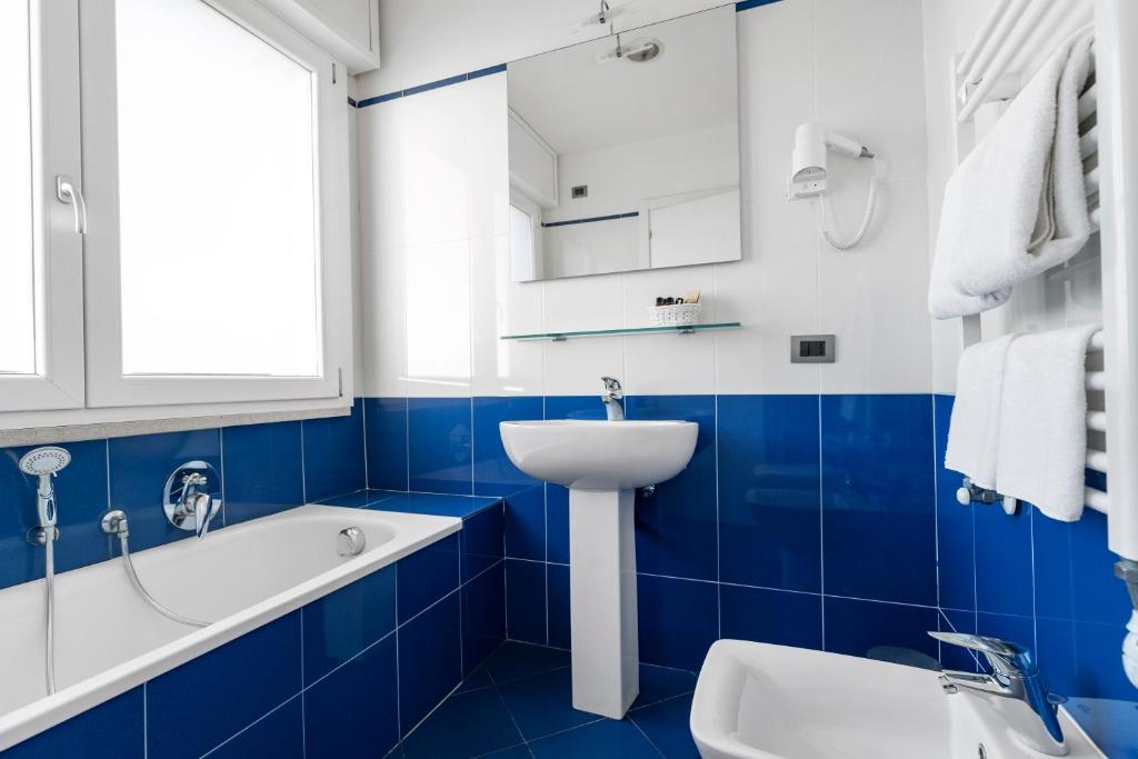 a blue and white bathroom with a sink and a bath tub at Hotel Sorriso in Venice-Lido