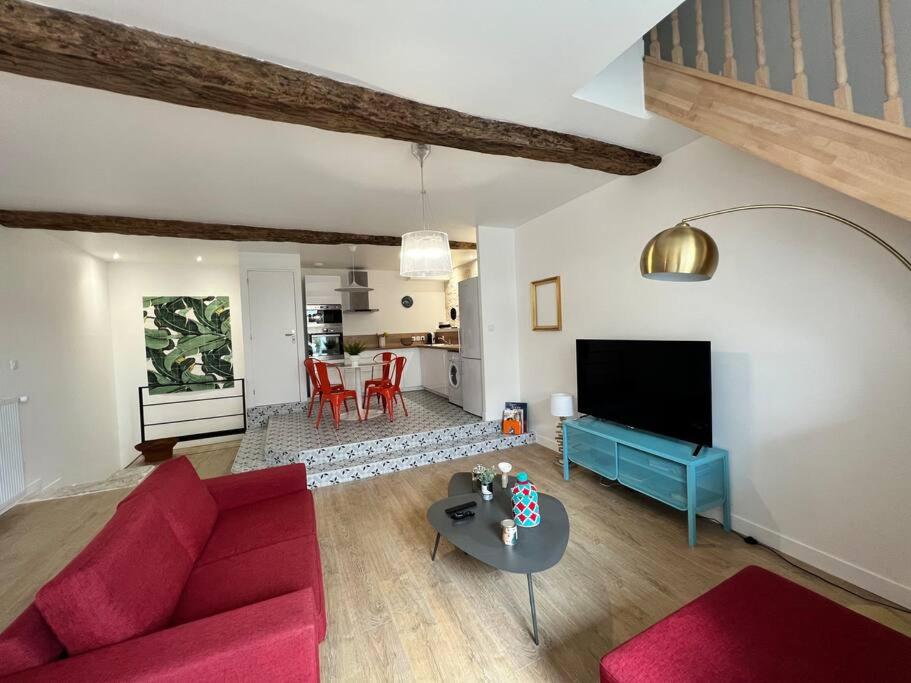 un salon avec un canapé rouge et une table dans l'établissement Maison de ville rénovée à 5 mn du Futuroscope, à Jaunay-Clan