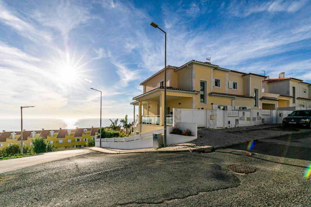 a house on a street with the sun in the sky at Vibing & Liming Ericeira in Ericeira