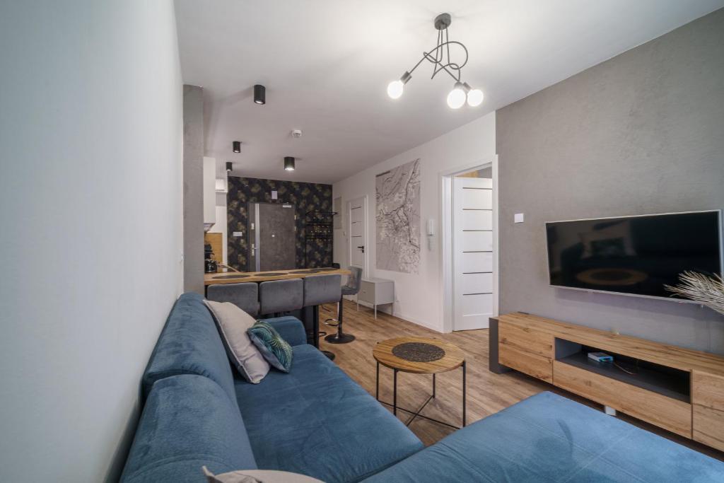 uma sala de estar com um sofá azul e uma televisão em Apartament16 Źródlana MountainAparts em Świeradów-Zdrój