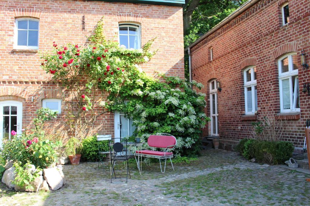 a brick building with two chairs and a bush with roses at Ferienwohnung Buchholz an der Müritz mit großem Naturgarten in Buchholz