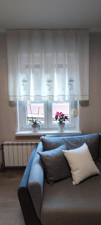 a blue couch in a living room with two windows at Apartma Soča Oasis in Srpenica