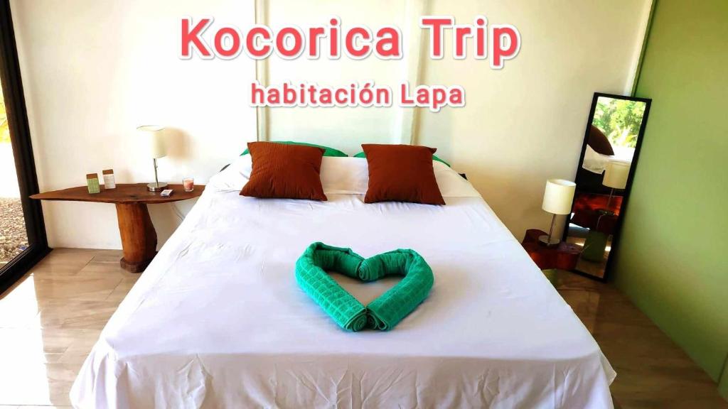 a bed with a green heart shaped pillow on it at Kocorica in Parrita