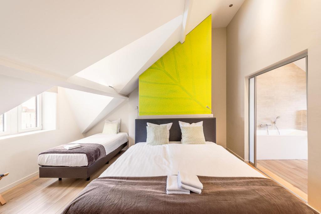 a bedroom with two beds and a yellow wall at Hotel Het Menneke in Hasselt