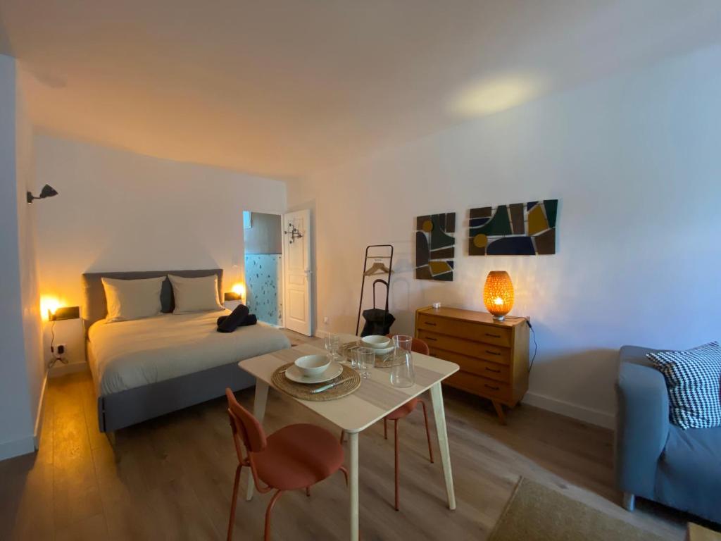 ein Schlafzimmer mit einem Bett, einem Tisch und einem Stuhl in der Unterkunft Le Confetti ! in Sète