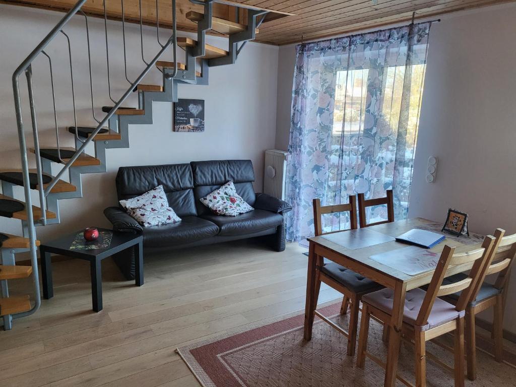 Una sala de estar con un sofá negro y una mesa. en Haus am Scharpenmoor, en Norderstedt