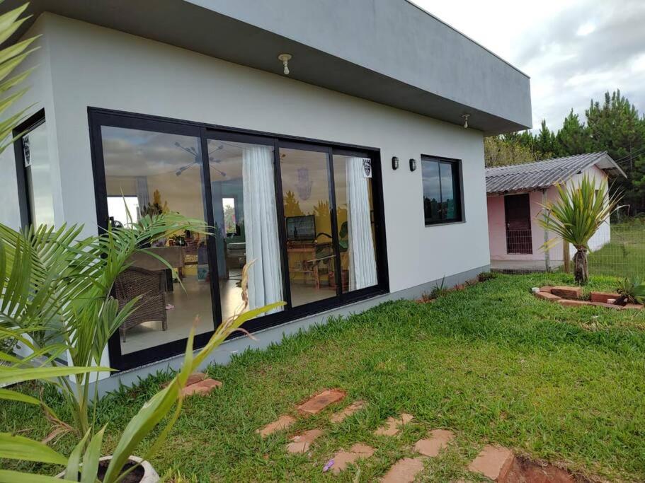 een huis met grote glazen schuifdeuren in een tuin bij Casa a 550m da praia e 350m da Lagoa da Tapera. in Passo de Torres