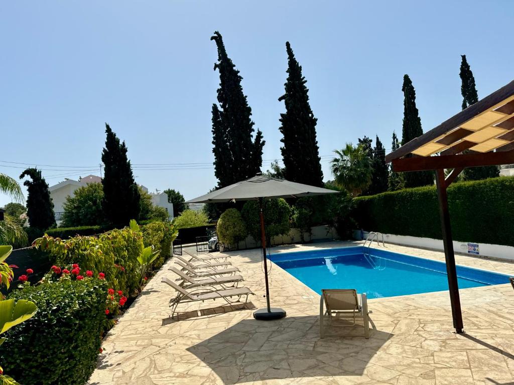 einen Pool mit einem Sonnenschirm, Stühlen und einem Tisch in der Unterkunft Villa Lorena Protaras in Protaras