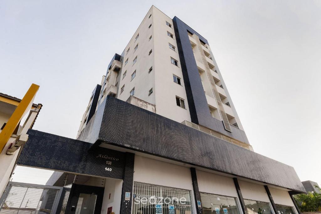un edificio blanco alto con muchas ventanas en EAO - Apartamentos completos em Joinville/SC, en Joinville