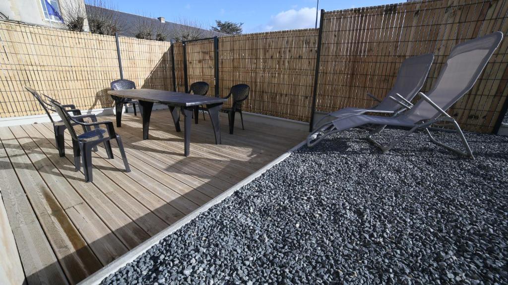 a patio with a table and chairs and a fence at Villa Joséphine 4-11 personnes in Asnelles