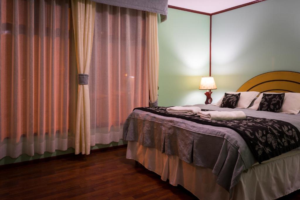 a bedroom with a large bed and a large window at Hostal Alcázar in Puerto Natales
