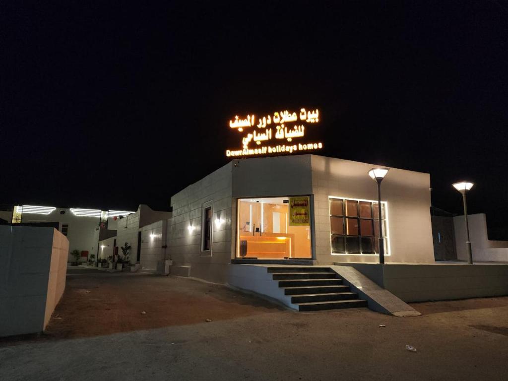 un bâtiment avec un panneau en haut de celui-ci la nuit dans l'établissement بيوت عطلات دور المصيف للضيافة السياحي, à Qarār