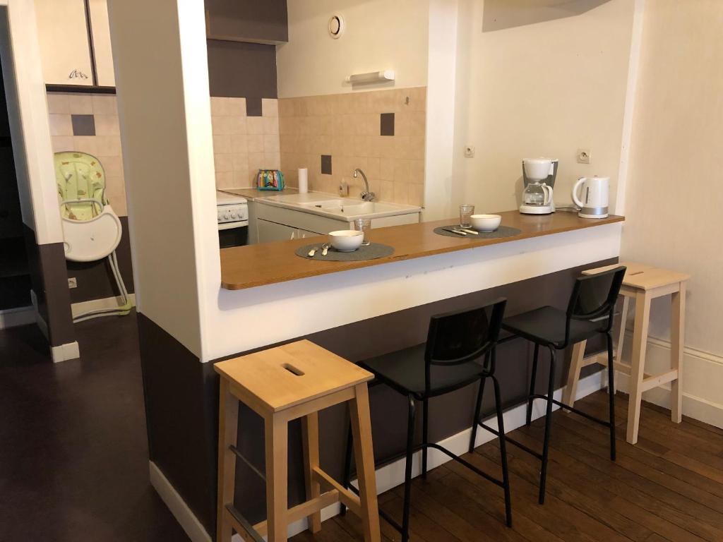 eine Küche mit einer Bar mit Hockern und einem Waschbecken in der Unterkunft Appartement centre ville Langres in Langres