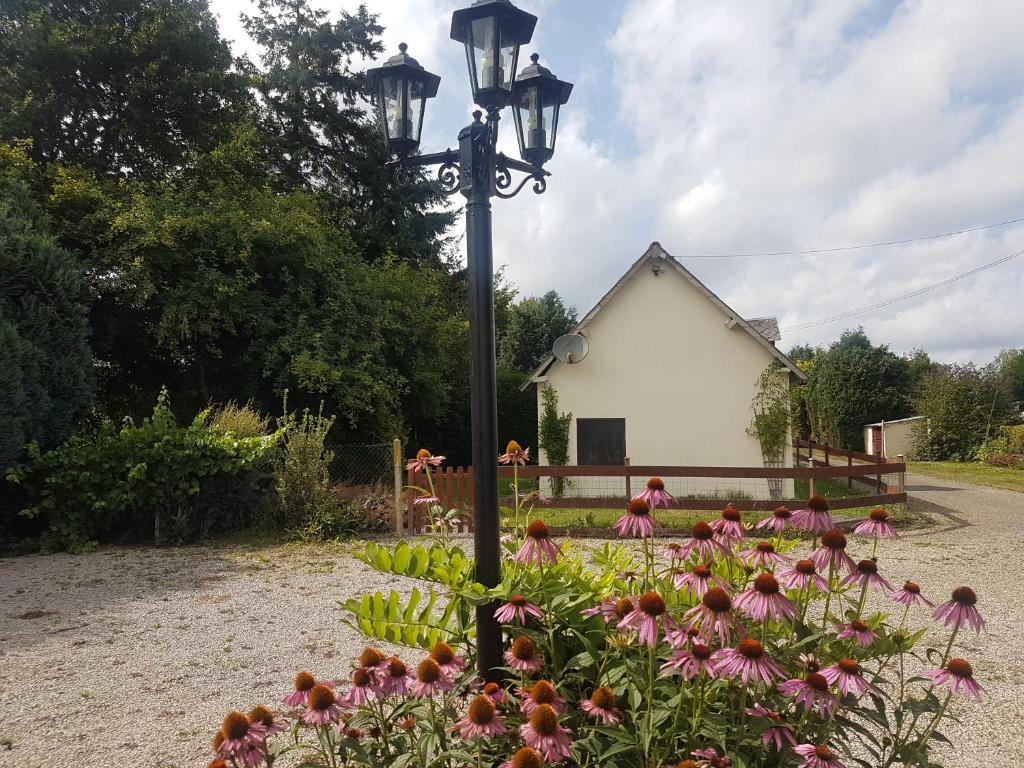 a street light with flowers in front of a house at Le gîte des Jardins d&#39;Hayden in Courson