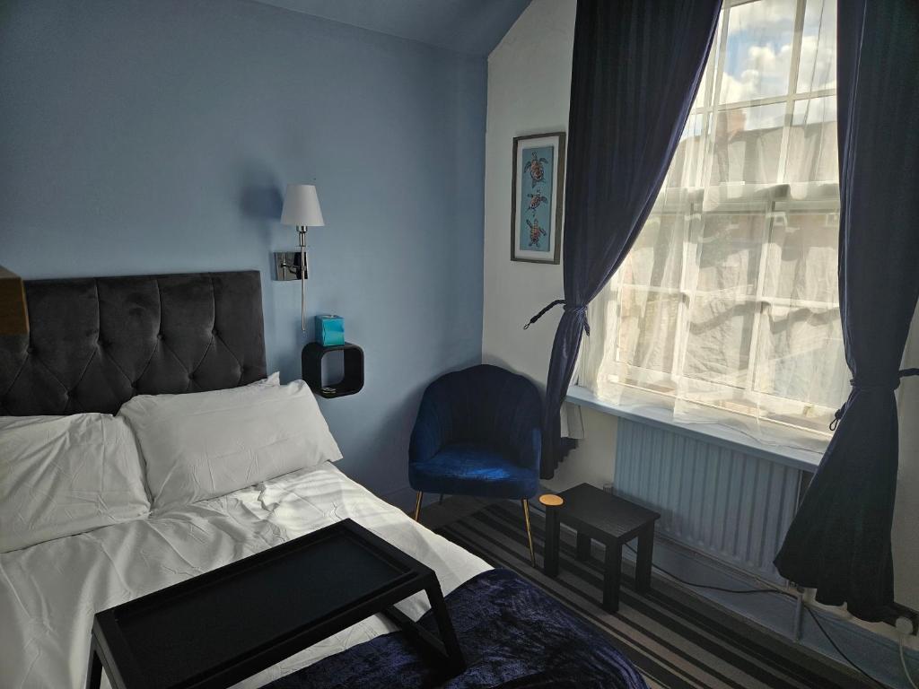 a bedroom with a bed and a chair and a window at Prime Location Room Stay in Northampton