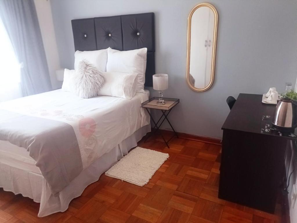 um quarto com uma cama com um espelho e uma mesa em MaThwala guesthouse em Vanderbijlpark