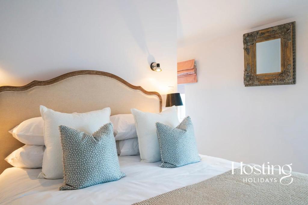 ein Schlafzimmer mit einem weißen Bett mit Kissen und einem Spiegel in der Unterkunft Greys View Cottage in Henley on Thames