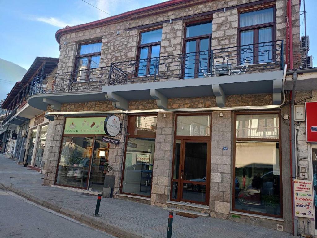 un bâtiment avec une horloge sur le côté d'une rue dans l'établissement MONOPATI HOUSE, à Mouzákion