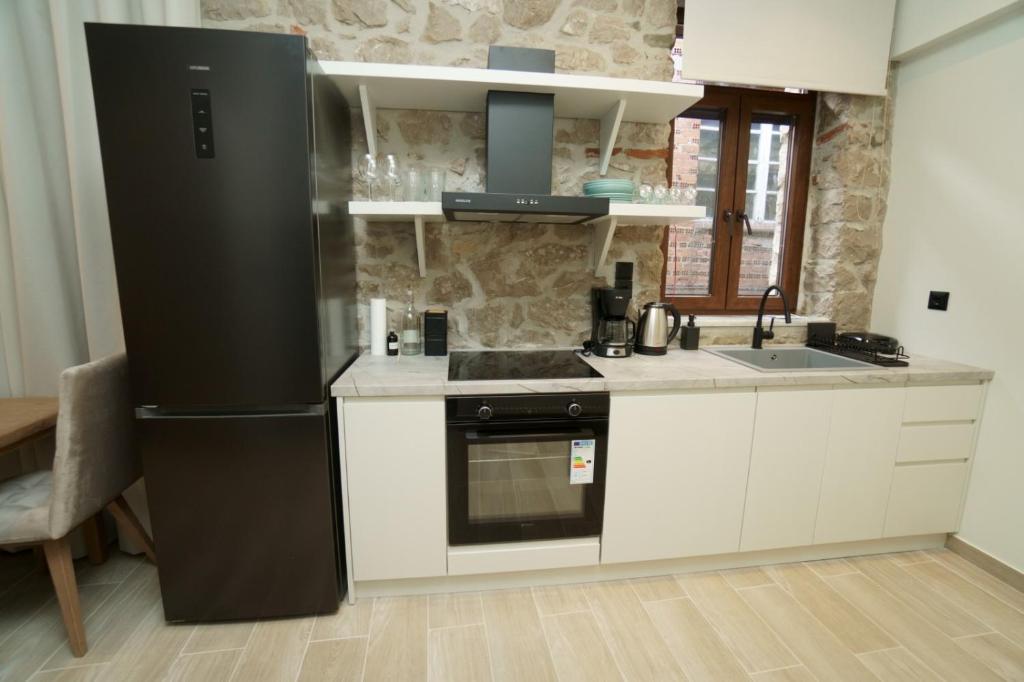 a kitchen with a black refrigerator and white cabinets at MONOPATI HOUSE in Mouzákion