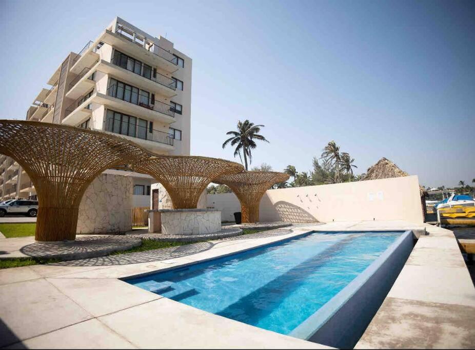 - une piscine avec une arche en osier à côté d'un bâtiment dans l'établissement Departamento Puerta Al Mar, à Conchal