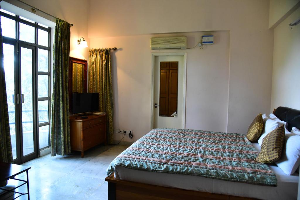 a bedroom with a bed and a tv and a window at Suite Room in Apartments in Bangalore
