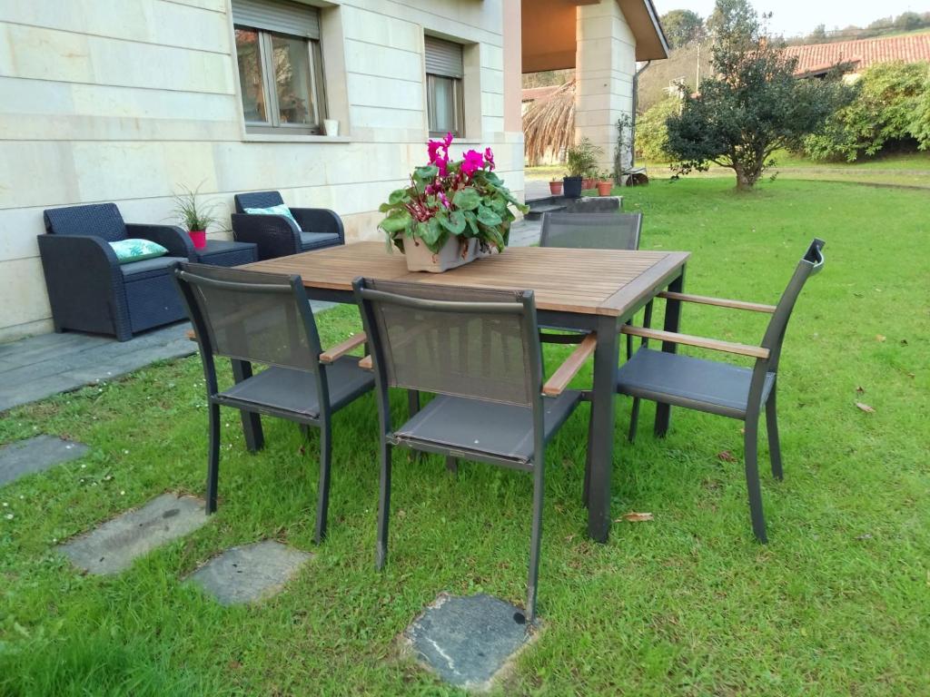 una mesa de madera con sillas y una maceta. en Puente Romano, en Galizano