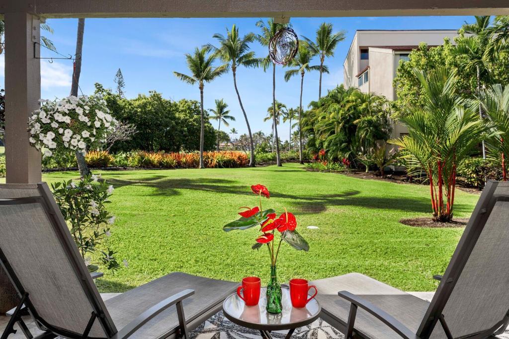 una mesa con un jarrón con flores rojas. en Keauhou Kona Surf & Racquet Club#7-102 "Honu Hale", en Kailua-Kona