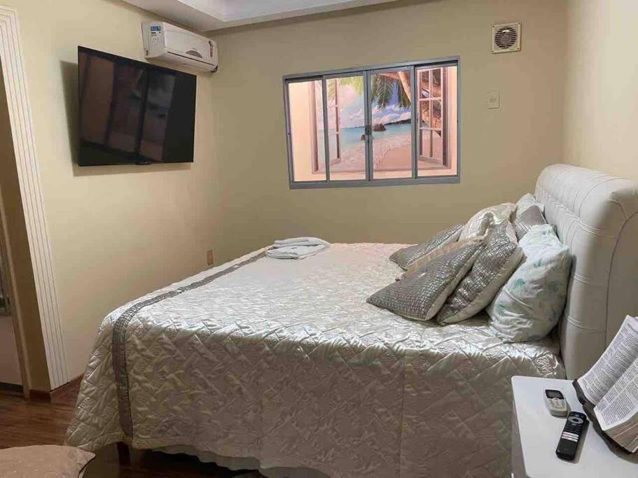 a bedroom with a bed and a flat screen tv at Apartamento Encantador C in Montes Claros