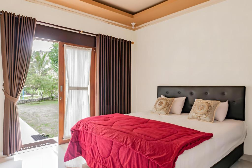 a bedroom with a large bed with a red blanket at Calm Haven Villa with Amabela Garden Lovina Beach in Lovina