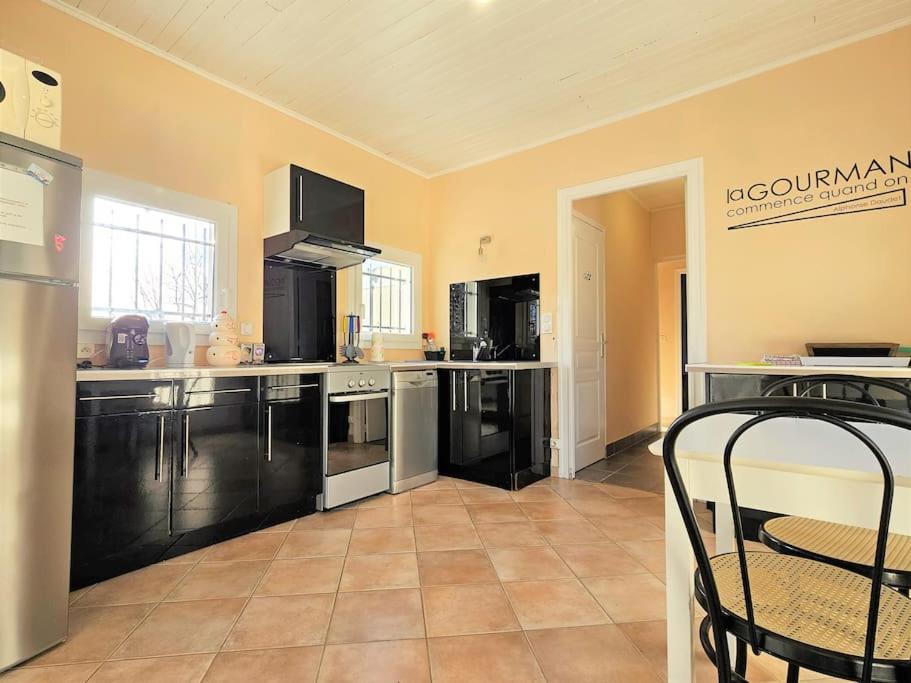 a large kitchen with black cabinets and appliances at Maison de campagne, au calme. in Carlux