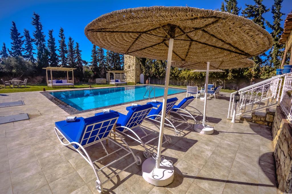 ein Pool mit blauen Stühlen und einem großen Sonnenschirm in der Unterkunft Villa jamal essaouira in Essaouira