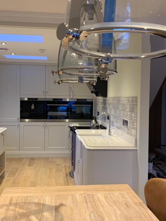 a kitchen with white cabinets and a sink at Luxury 5 Star House - Ard Craig House Ballachulish Glencoe in Glencoe